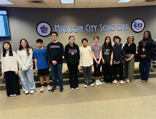 9 Journey Middle School  band members with director and principal standing in front of the Board meeting